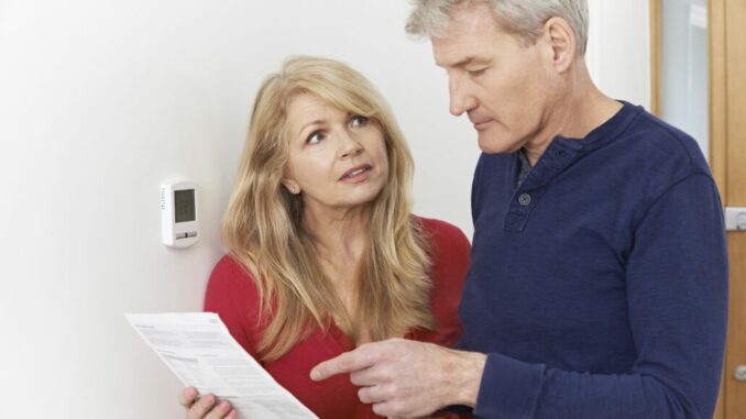 Worried Mature Couple With Bill Turning Down Central Heating