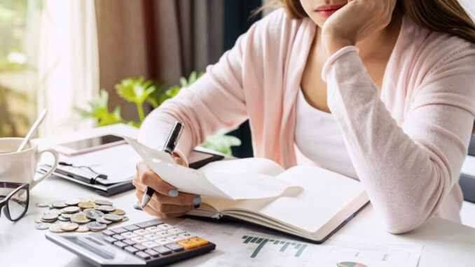 Stressed young woman calculating monthly home expenses, taxes, bank account balance and credit card bills payment, Income is not enough for expenses.