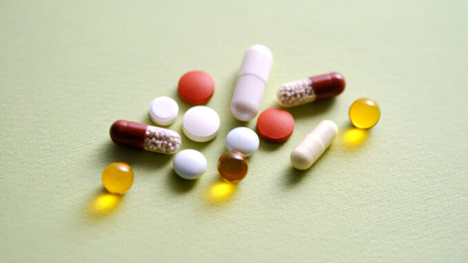 Pills, vitamins and dietary supplements on a green background.
