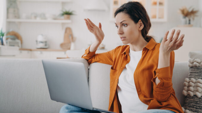 Puzzled european woman with laptop is talking at internet meeting and telling a problem.