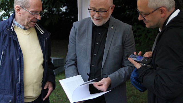 Michael Stephan, Pfarrer Günter Ernst und Pastoralreferent Martin Grote werfen einen Blick in das Buch. Foto: Christian Zimmer